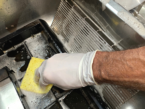 Image shows washing of the drip trays with a sponge and mild soapy water.