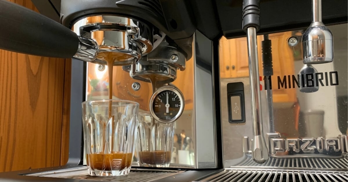 Naked portafilter extracting balanced espresso into a piccolo glass to demonstrate proper shot timing and prevent coffee bitterness